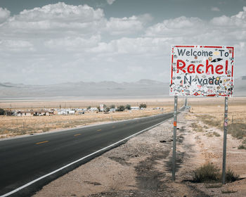 Information sign on road against sky