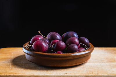 Still life of cherries in a ceramic bowl on a kitchen wooden board