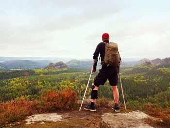 Man hiker wearing supportive leg brace and gainst the cruthes. natural forest park in background