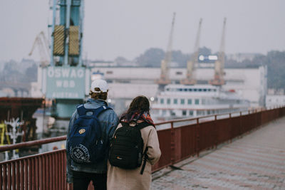 Rear view of men standing on bridge in city