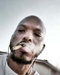 Close-up of man smoking blunt against sky