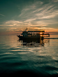 Silhouette ship in sea against sky during sunset