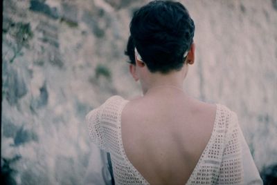 Rear view of shirtless woman standing against blurred background