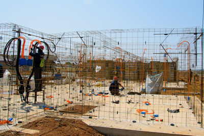 People working at construction site against sky