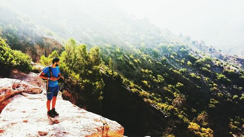 High angle view of male hiker with backpack looking at view while standing on mountain