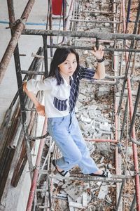 Full length portrait of woman standing against ladder