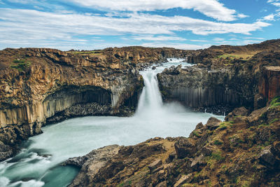 Scenic view of waterfall against sky