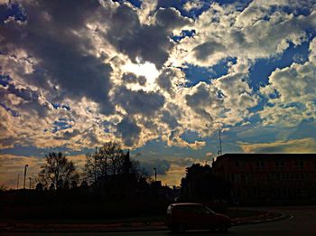 Cars parked on road against cloudy sky