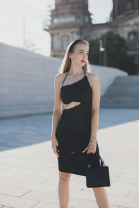 Portrait of young woman standing in city