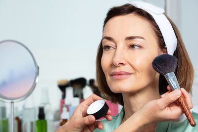 Portrait of young woman holding thermometer