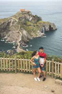 Full length of couple standing by railing against sea