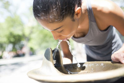 Female athlete drinking water from well