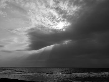 Sunlight streaming through clouds over sea