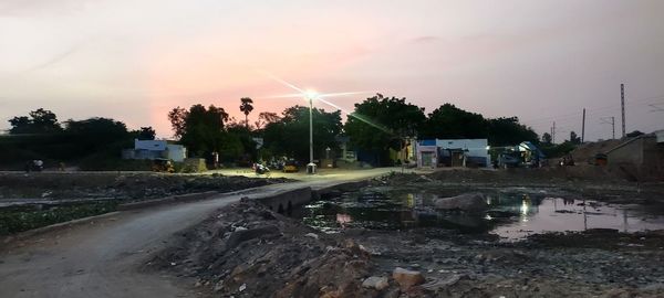 Road by city against sky during sunset