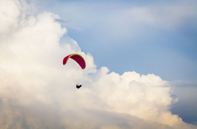 Low angle view of person paragliding against sky