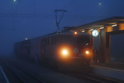 Train at railroad station platform against sky at night