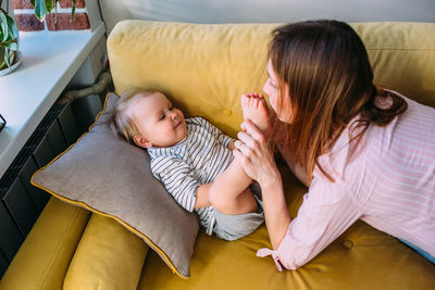 Mom plays at home with a small child on the couch, have fun.