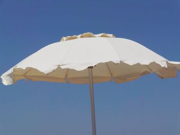 Low angle view of umbrella against clear blue sky