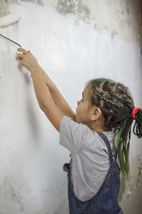 Side view of woman standing against wall