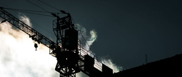 Low angle view of silhouette crane against sky at dusk