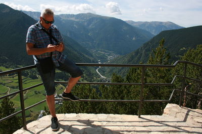 Full length of mature man standing by railing on cliff