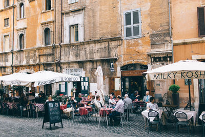 Group of people at sidewalk cafe against buildings in city