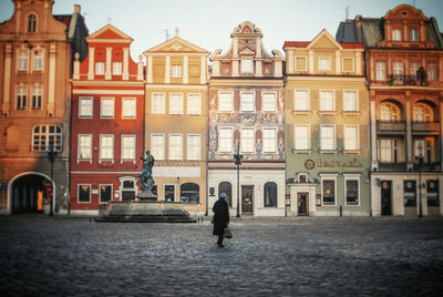 Woman walking on street against buildings