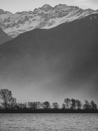 Scenic view of lake by mountains against sky during winter