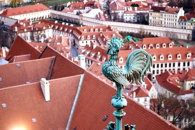 Close-up of rooster weather vane on top of st vitus cathedral with cityscape