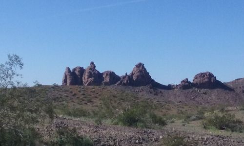 Rock formations on landscape against clear blue sky