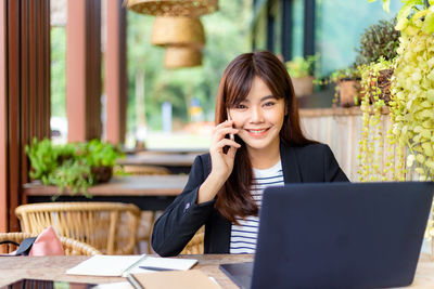 Young woman using phone while sitting on table