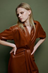 Portrait of young woman standing against wall