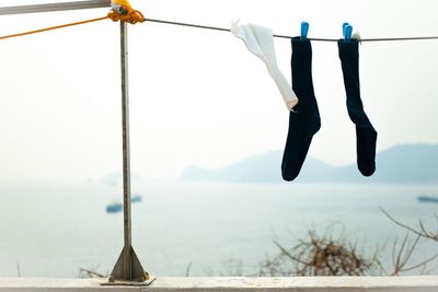 Close-up of clothes drying on clothesline against sky