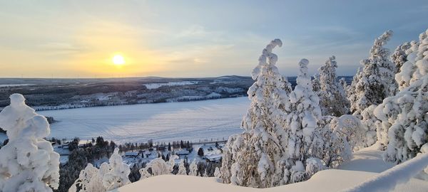 Scenic view of snow covered landscape against sky during sunset