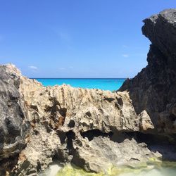 Rock formations on beach against blue sky