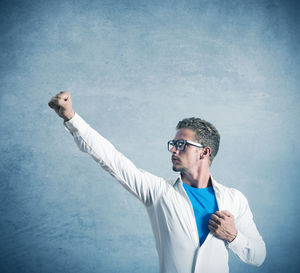 Man wearing sunglasses standing against blue background