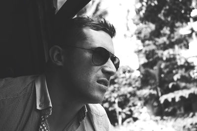 Close-up of man wearing sunglasses looking outside window