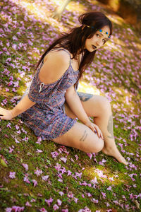 Portrait of young woman sitting on flowers in park
