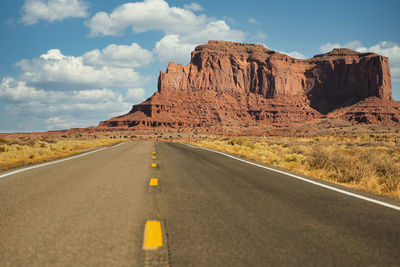 Road leading towards mountains against sky