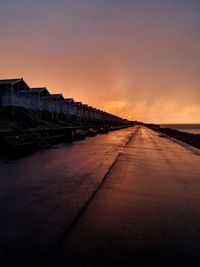 Road by city against sky during sunset