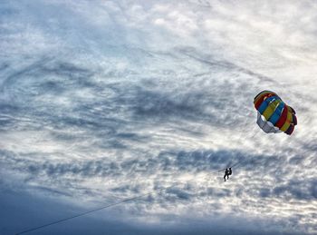 Low angle view of person paragliding against sky