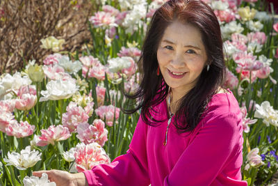 Portrait of smiling woman with pink flowering plants