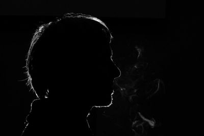 Close-up of man smoking against black background