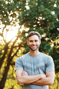 Portrait of young man standing against trees