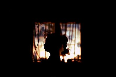 Silhouette man and woman standing against dark sky