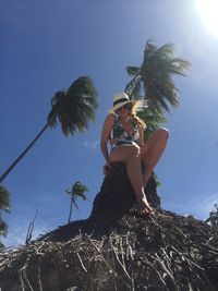 Low angle view of woman on palm tree against sky