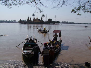 People on boat in river against sky