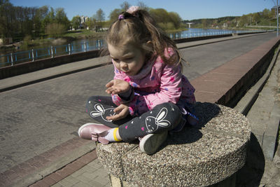 Full length of cute girl sitting outdoors