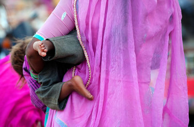 Rear view of mother carrying child while walking on road