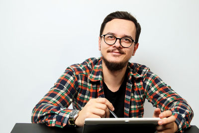 Portrait of young man sitting on sofa against white background